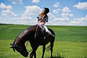 jeune jolie fille à cheval sur un champ à la journée ensoleillée. photo