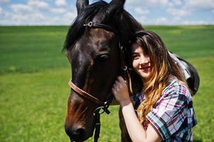jeune jolie fille reste à cheval sur un champ à la journée ensoleillée. photo