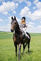 jeune jolie fille à cheval sur un champ à la journée ensoleillée. photo