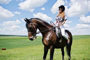 jeune jolie fille à cheval sur un champ à la journée ensoleillée. photo