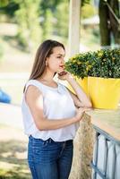 portrait d'une jeune fille fantastique posant à côté d'un pot de fleurs à l'extérieur dans le parc. photo