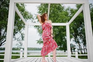 portrait d'une fabuleuse jeune fille vêtue d'une tenue chic posant sur une terrasse en bois blanc. photo