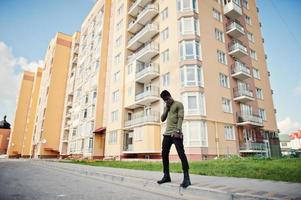 beau et séduisant homme afro-américain posant à côté du grand bâtiment dans une rue. photo