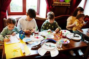 préparation au concept de pâques. enfants avec mère faisant à la main des lapins et des œufs. photo