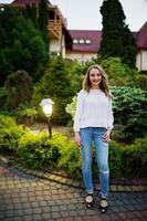 fabuleuse demoiselle d'honneur portant un jean et un t-shirt blanc posant à l'extérieur lors d'une soirée entre célibataires. photo