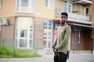 beau et séduisant homme afro-américain posant à côté du grand bâtiment dans une rue. photo