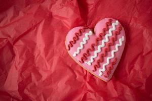 Biscuits en forme de coeur rose avec détail de glaçage sur fond rouge photo