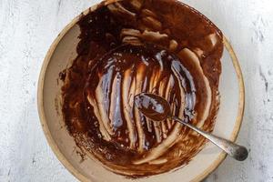 bol et cuillère de ferme avec des restes de mélange de brownie à plat photo