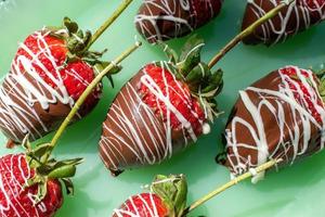 fraises aux tiges trempées dans du chocolat et arrosées de chocolat blanc sur verre vert à plat photo