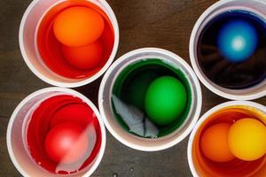 vue de dessus de tasses d'eau et de colorant de couleur différente avec des œufs immergés photo
