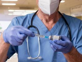 médecin senior prenant une dose de vaccin covid-19 à partir d'une bouteille photo