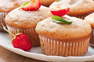 Muffin aux fraises sur une plaque blanche avec une fraise fraîche photo