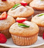 Muffin aux fraises sur une plaque blanche avec une fraise fraîche photo