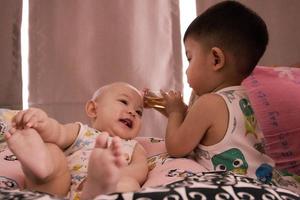 le bébé soeur asiatique jouant avec son bébé garçon dans le salon. photo