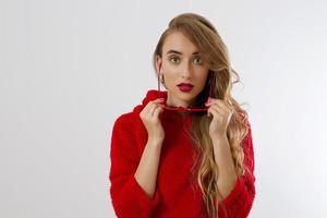 gros plan visage de femme avec des lèvres rouges, lunettes de soleil à capuche isolé sur fond blanc. fille à la mode en tenue élégante. maquillage, concept de beauté. vêtements d'automne d'hiver. visage féminin excité par le choc. fermer photo