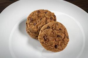 assiette de biscuits aux pépites de chocolat fraîchement cuits. fond en bois, mise au point sélective photo