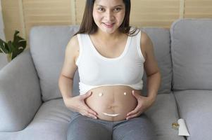 jeune femme enceinte appliquant une crème hydratante sur le ventre, les soins de santé et les soins de grossesse photo