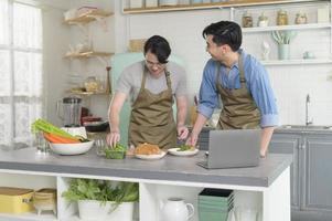 jeune couple gay souriant cuisinant ensemble dans la cuisine à la maison, lgbtq et concept de diversité. photo