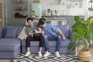 jeune couple gay souriant jouant à des jeux vidéo dans le salon à la maison, lgbtq et diversité photo