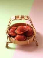 vue en grand angle du gâteau de tortue rouge dans un petit panier de bambou avec fond vert et rose. photo