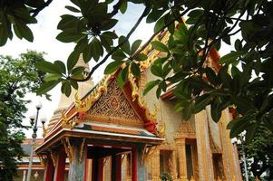 Temple d'or thaïlandais à travers l'ombre des arbres photo