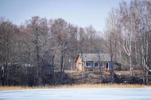 vieille maison debout sur la rive du lac couverte de neige photo