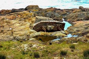 Vieux bateau naufragé rouillé sur une côte rocheuse photo