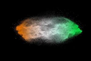 explosion de particules de poussière orange vert sur fond noir. éclaboussures de poussière de poudre de couleur. photo