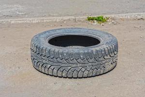 jeté sur une route déserte, un vieux pneu d'hiver usé d'une roue de voiture photo