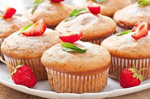 Muffin aux fraises sur une plaque blanche avec une fraise fraîche photo