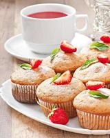 Muffin aux fraises sur une plaque blanche avec une fraise fraîche photo