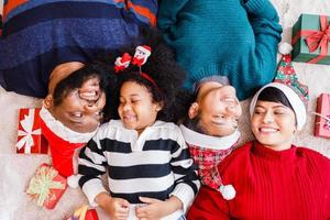 famille afro-américaine sur le thème de noël. heureuse famille afro-américaine de quatre personnes allongées sur le sol ensemble. photo