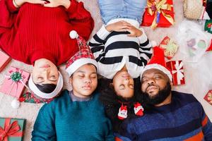 famille afro-américaine sur le thème de noël. heureuse famille afro-américaine de quatre personnes allongées sur le sol ensemble. photo