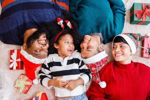 famille afro-américaine sur le thème de noël. heureuse famille afro-américaine de quatre personnes allongées sur le sol ensemble. photo