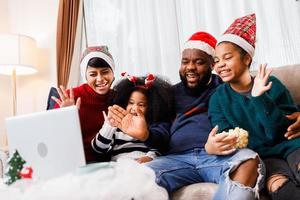 une famille afro-américaine s'amuse pendant un appel vidéo sur un ordinateur portable et s'assoit ensemble sur le canapé photo