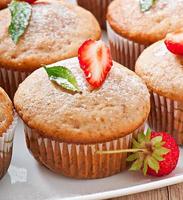 Muffin aux fraises sur une plaque blanche avec une fraise fraîche photo