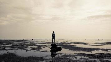 un homme debout sur un rocher près de la plage photo