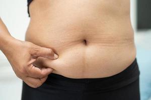 une femme asiatique en surpoids montre un gros ventre au bureau. photo