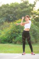 une belle femme asiatique s'échauffe, pour assouplir les muscles avant d'aller faire du jogging photo