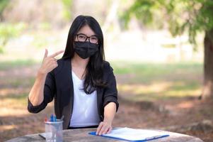 les femmes d'affaires asiatiques doivent utiliser un masque facial pour prévenir la pollution par la poussière et prévenir l'infection virale, lors de l'épidémie du virus corona qui doit travailler à la maison photo