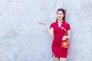 belle femme asiatique en robe rouge se dresse tenant un sac rouge parmi le thème du nouvel an chinois du vieux centre-ville. photo