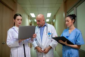 groupe de médecins consultant les dossiers des patients, médecin âgé et collègue discutant de la thérapie actuelle de la maladie sur le lieu de travail. photo