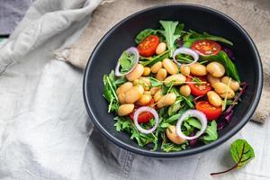 Salade de haricots tomate, oignon, feuilles de laitue mélanger des repas de légumes frais et sains collation diététique sur la table copie espace arrière-plan alimentaire photo