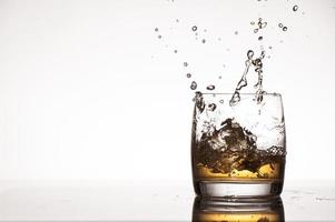 éclaboussures de glace dans le whisky ou le brandy photo