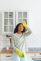 femme afro-américaine se sentant soulagée après avoir fini de nettoyer la cuisine. fatigué des tâches ménagères