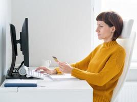 concept d'achat en ligne. femme paie ses achats par carte de crédit. vue latérale d'une femme d'âge moyen photo