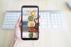 livraison de nourriture sans contact. application sur votre téléphone. écran de téléphone portable. la personne tient un smartphone photo