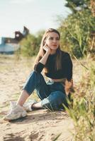 pleine longueur belle femme pensive assise sur la plage au coucher du soleil en soirée. jolie femelle photo