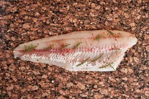 filet de poisson de sandre cru frais sur une table en marbre brun foncé. vue de dessus photo