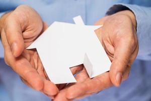 homme tenant une maison de papier dans ses mains photo